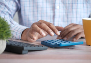 A photo of a man's hands as he uses a calculator