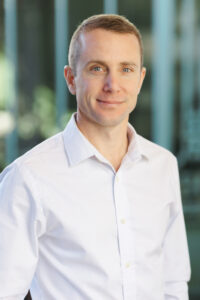 Photo of Taylor Gray wearing a white shirt standing in front of a blurred background